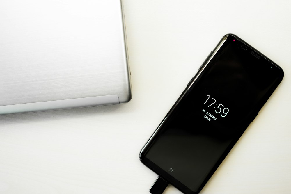 Celular conectado al cargador sobre una mesa blanca, contacto de Técnico Celulares Ya
