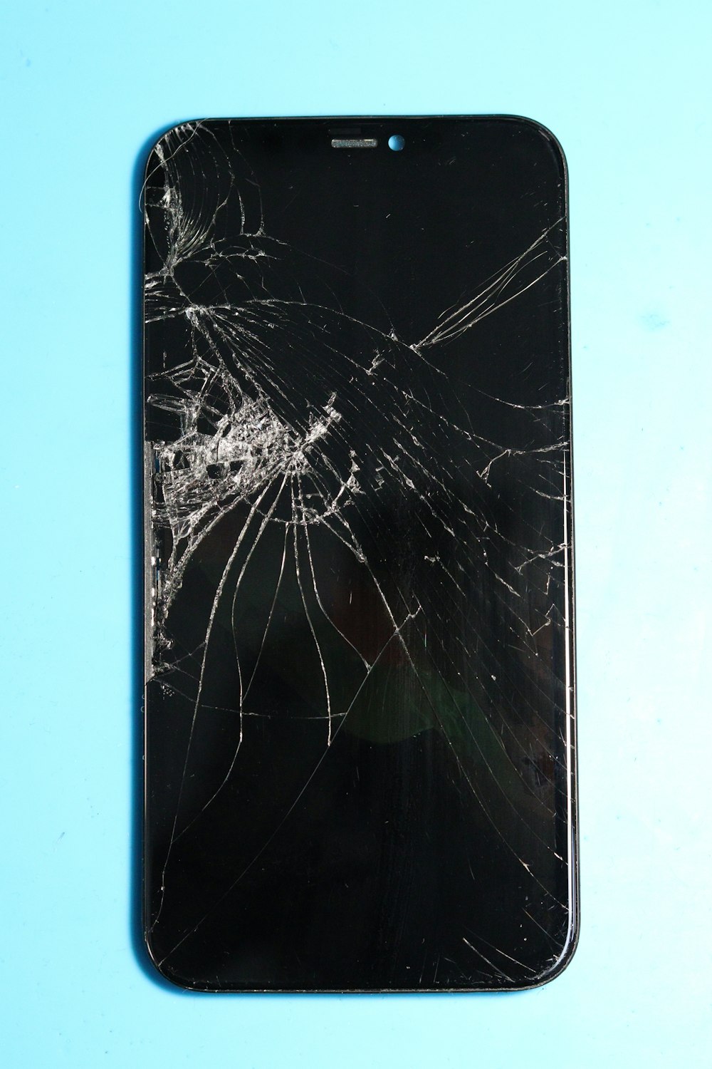 Celular con la pantalla trizada sobre un fondo celeste en su comuna